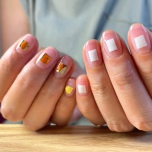 ワンポイントのアートをしたアシンメトリーなクリアネイルでポージングをしている手元のアップ