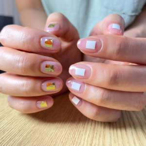 ワンポイントのアートをしたアシンメトリーなクリアネイルでポージングをしている手元のアップ