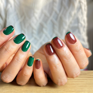 ブラウンとグリーンのアシンメトリーフレンチネイルでポージングをしている手元のアップ