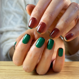 ブラウンとグリーンのアシンメトリーフレンチネイルでポージングをしている手元のアップ