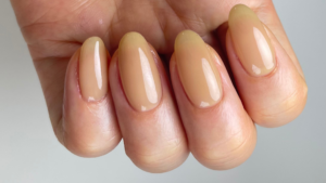 ヌードベージュのワンカラーネイルをした指先のアップ