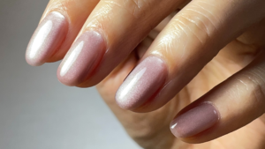 ピンクベージュのマグネットネイルのワンカラーネイルをした指先のアップ