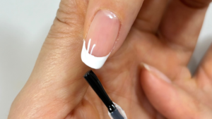 フレンチネイルネイルにトップコートをしている手元のアップ