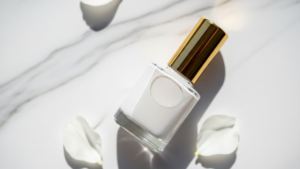 白いマニキュアが入ったボトルが白い花びらと一緒におかれいる