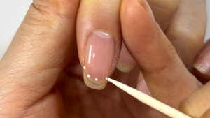 爪楊枝でフレンチネイルのガイドを描いている