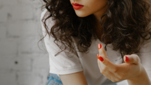 赤い口紅と赤いネイルをした女性の上半身