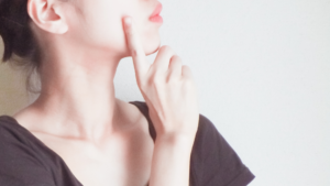 人差し指を顔に添えて考えている様子の女性の横顔
