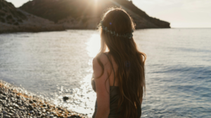 海辺で女性が歩いている様子。逆光ではっきりした姿は分からない