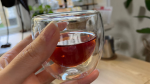 お茶が入った小さいカップを手にもっているアップ