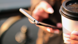 左手にドリンクカップ、右手にスマホをもっている女性の手元