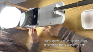 三脚にスマホをセットしてセルフネイルの撮影をしている女性